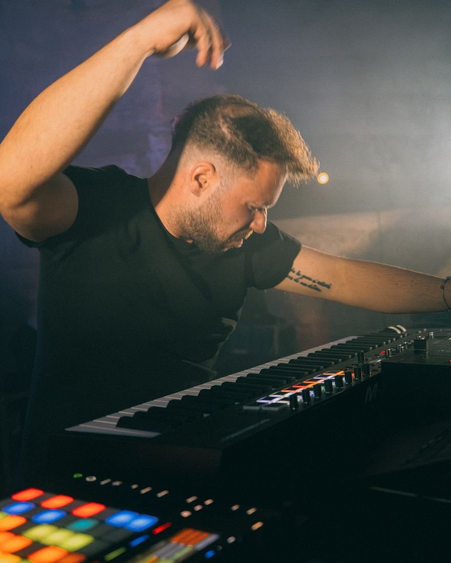 Alessio al suo set live, tra tastiera e pad, con il braccio alzato